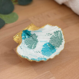 Repose bijoux original coquillage corail turquoise vu de face sur support bois.