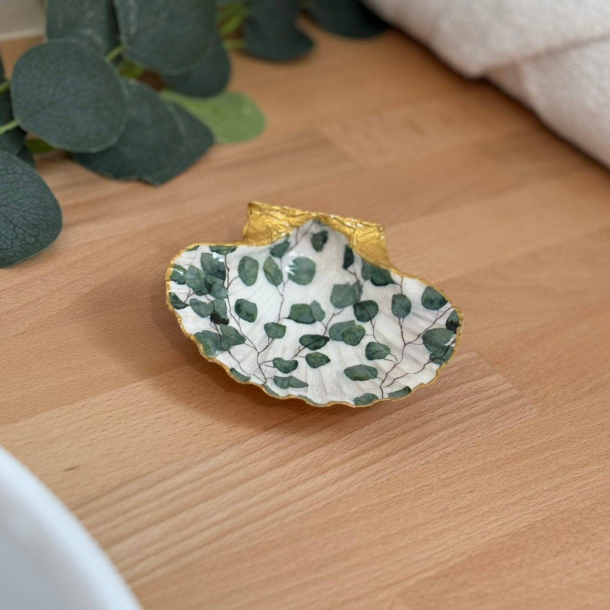 Mise en ambiance Repose bijoux original coquillage eucalyptus vert sauge en décoration sur meuble bois.