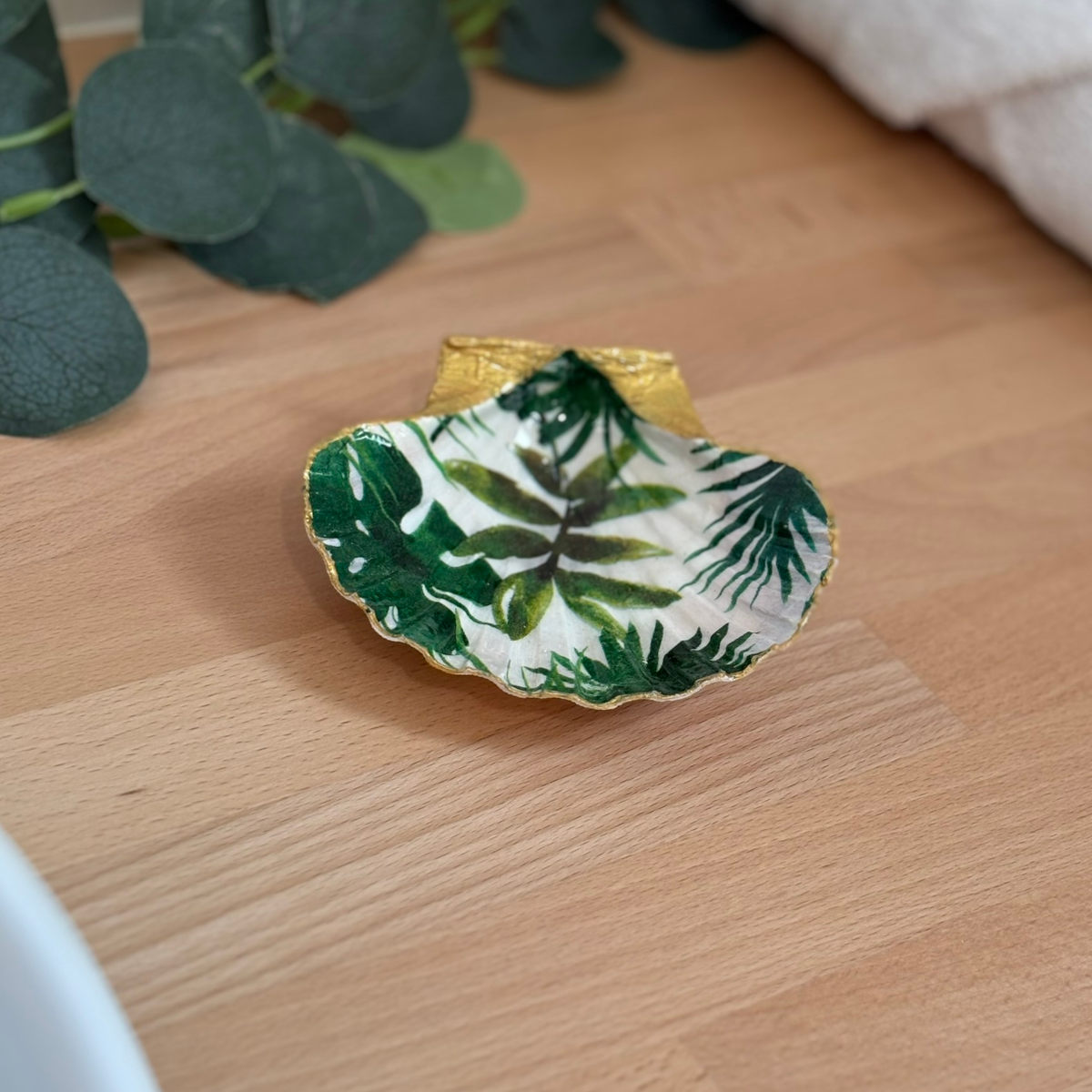 Mise en ambiance Repose bijoux original coquillage feuillage tropical vert en décoration sur meuble bois.