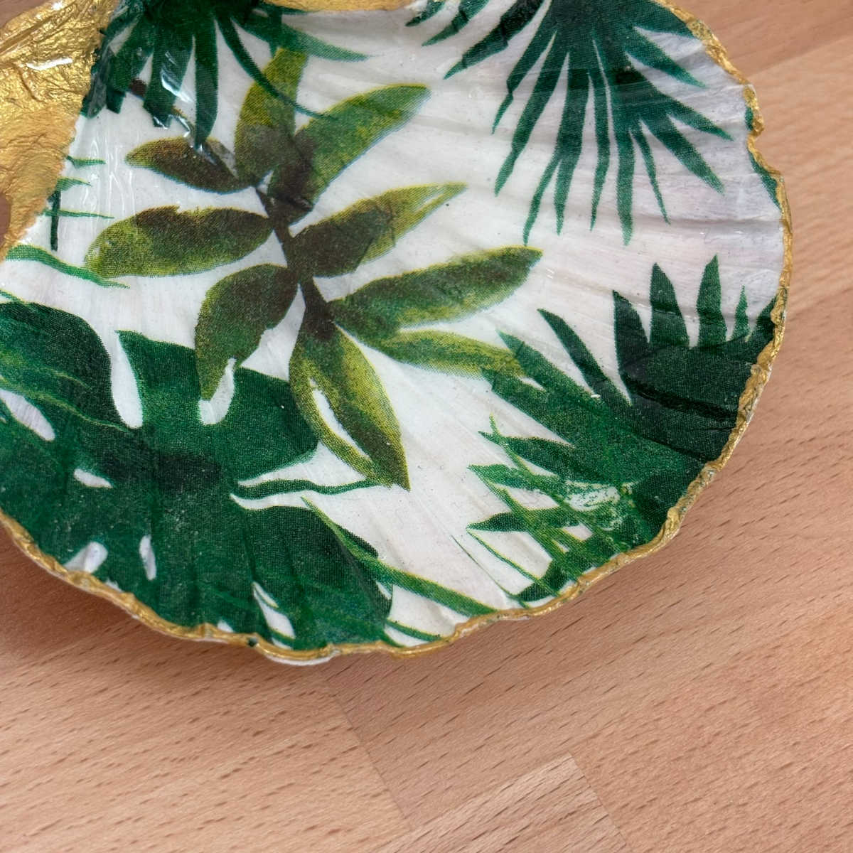 Détail intérieur Gros plan du repose bijoux original coquillage feuillage tropical vert au centre.