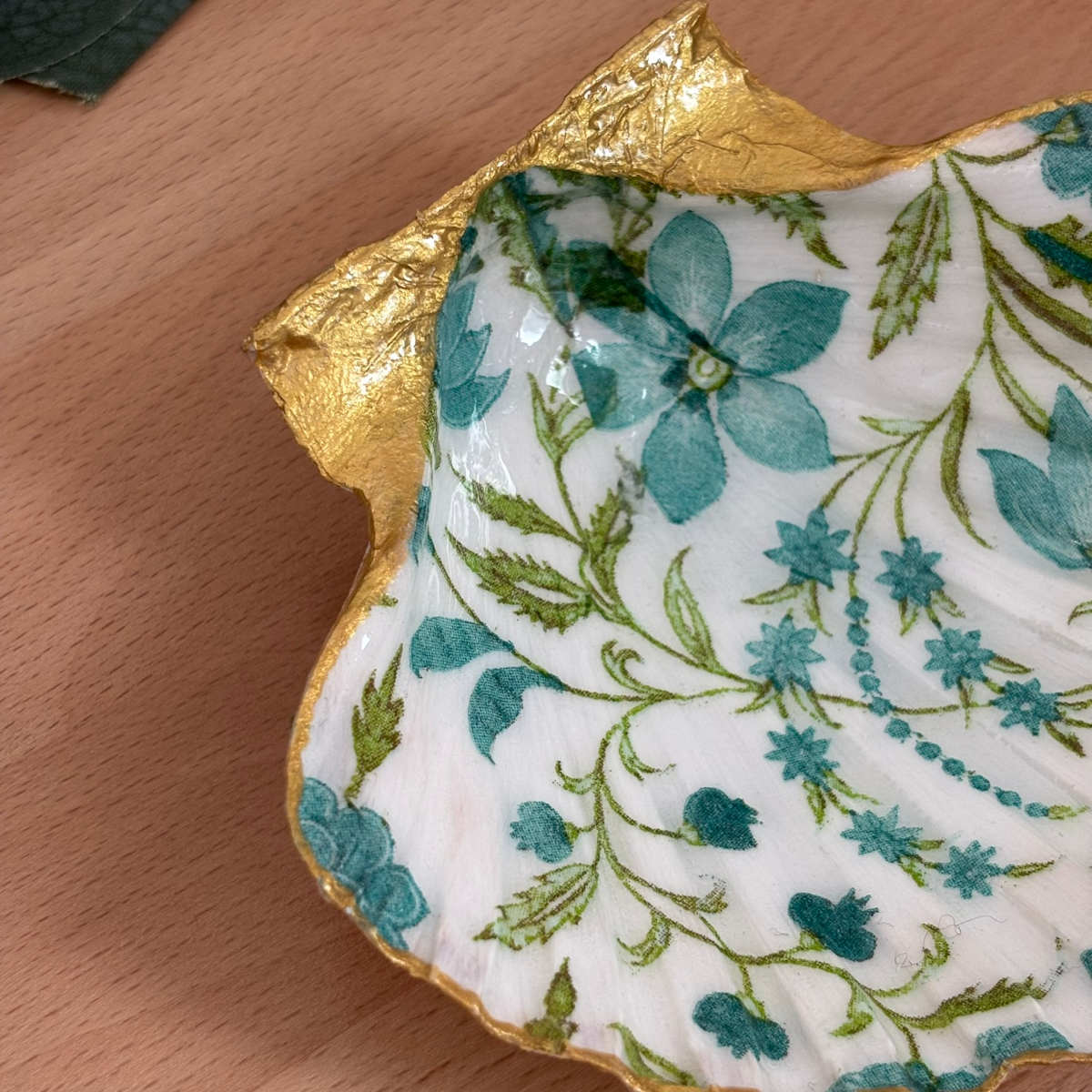 Détail finition dorée Détail du repose bijoux original coquillage fleurs bleu canard avec bordure dorée.