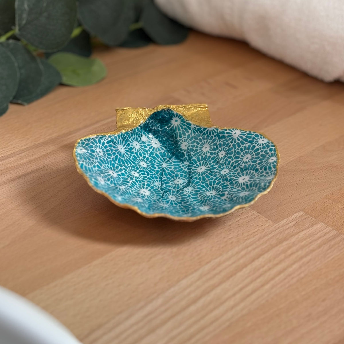 Mise en ambiance Repose bijoux original coquillage fleurs turquoise en décoration sur meuble bois.