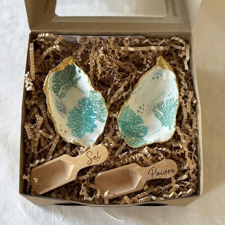 Coffret ouvert – contenu du duo sel & poivre Coffret ouvert contenant deux coquilles d’huîtres décorées et cuillères gravées