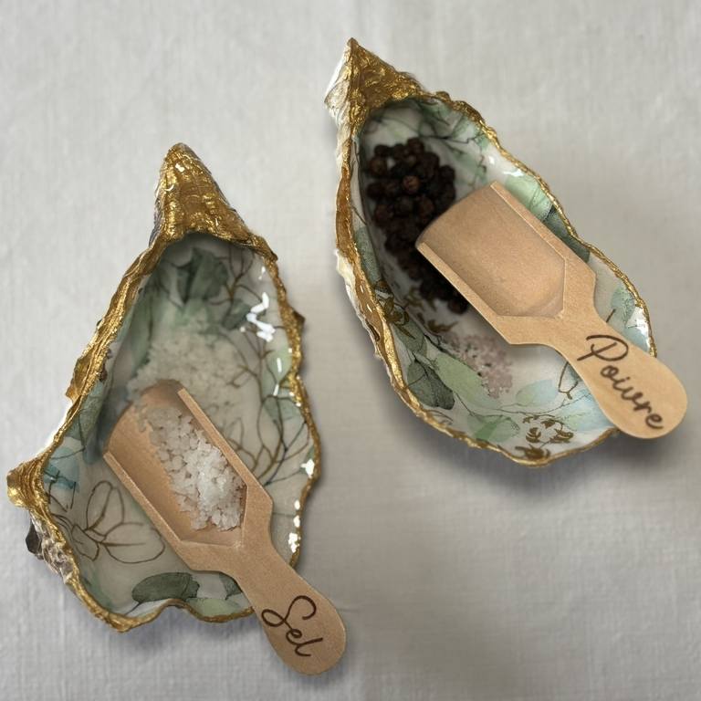 Salière et poivrière motif feuillage en situation avec sel et poivre Salière et poivrière remplies de sel et poivre, motif végétal vert et doré