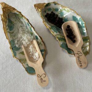 Gros plan sur les coquilles en forme naturelle décorées de fleurs bleues, dorées à la main, avec cuillères à sel et poivre.