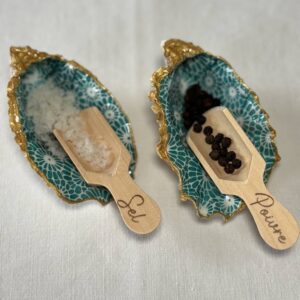 Salière et poivrière turquoise garnies de sel et poivre, en situation sur table