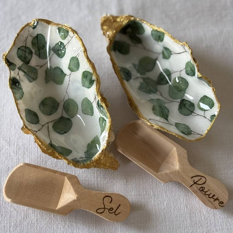 Vue du duo – feuilles d’eucalyptus sur fond blanc Salière et poivrière en coquilles d’huîtres dorées avec motif eucalyptus