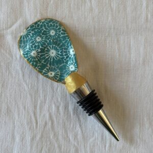 Bouchon de vin en coquille d’huître décorée de motifs géométriques bleu-vert et dorés.