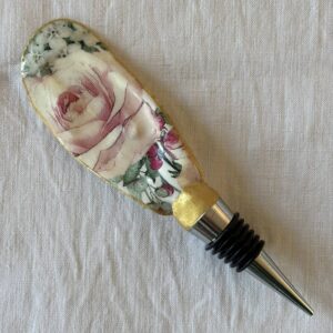 Bouchon de vin original en coquille d’huître, décoré d’une rose ancienne peinte à la main, fond blanc.