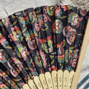 Détail du tissu noir fleuri d’un éventail original en bambou