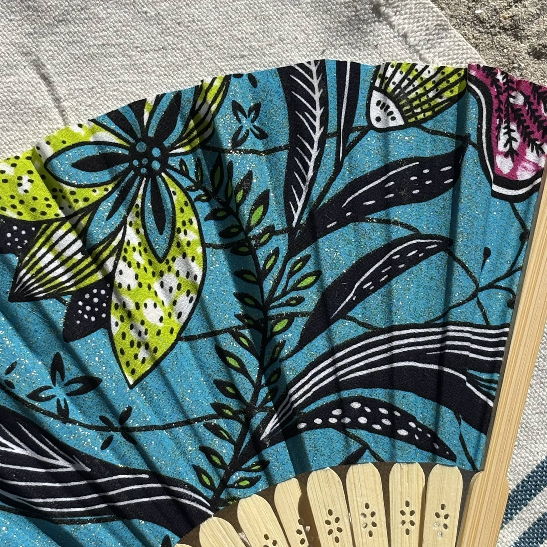 Gros plan sur le tissu fleuri turquoise et ses couleurs éclatantes Détail du tissu turquoise à motifs floraux d’un éventail original en bambou