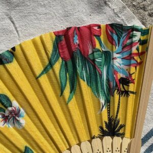 Détail du tissu tropical jaune à fleurs et palmiers d’un éventail original