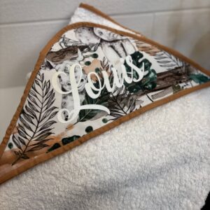 Détail du tissu feuillage et animaux de la cape de bain personnalisée Louis