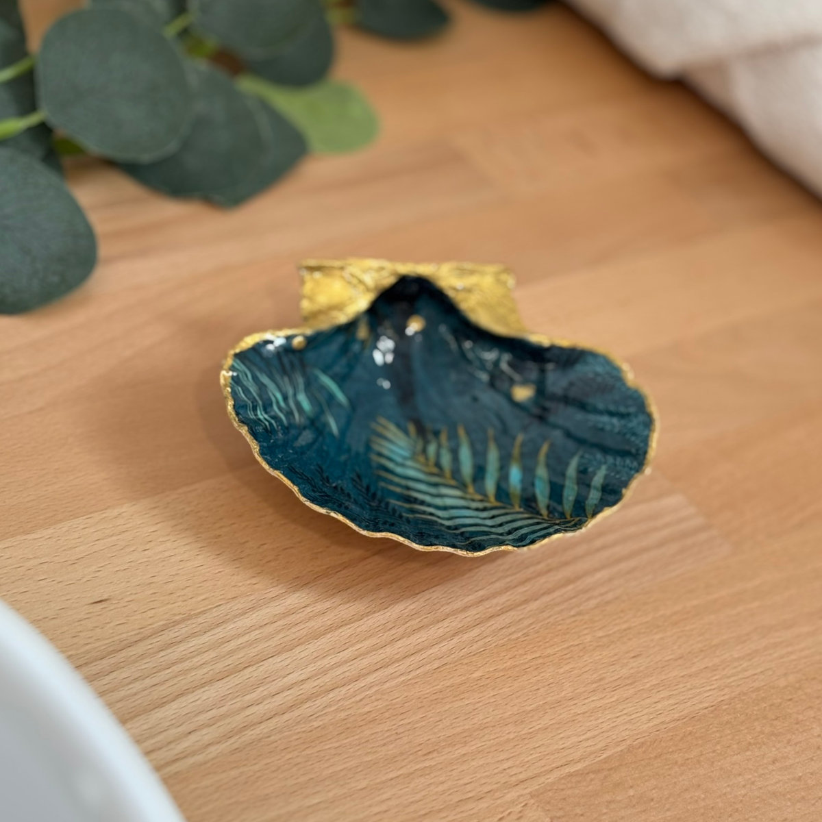Mise en ambiance Repose bijoux original coquillage bleu nuit doré en décoration sur meuble bois.