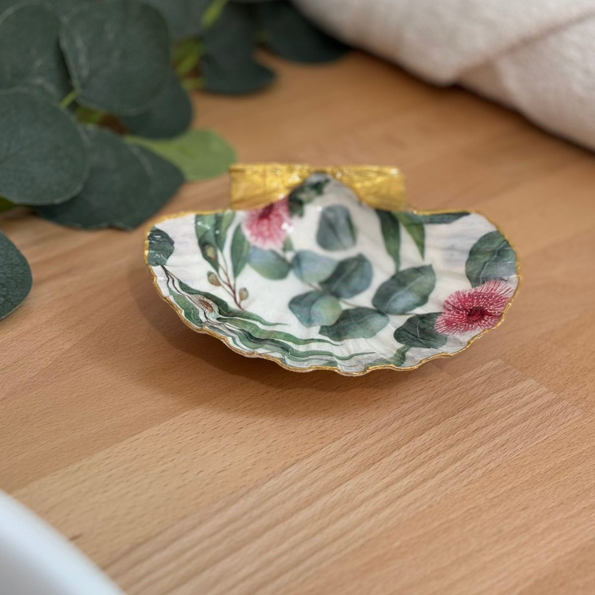 Mise en ambiance Repose bijoux original coquillage eucalyptus fleuri en décoration sur meuble bois.