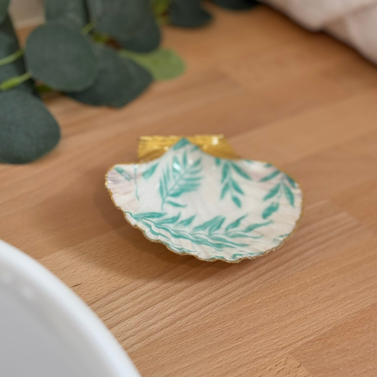 Mise en ambiance Repose bijoux original coquillage feuillage vert d’eau en décoration sur meuble bois.
