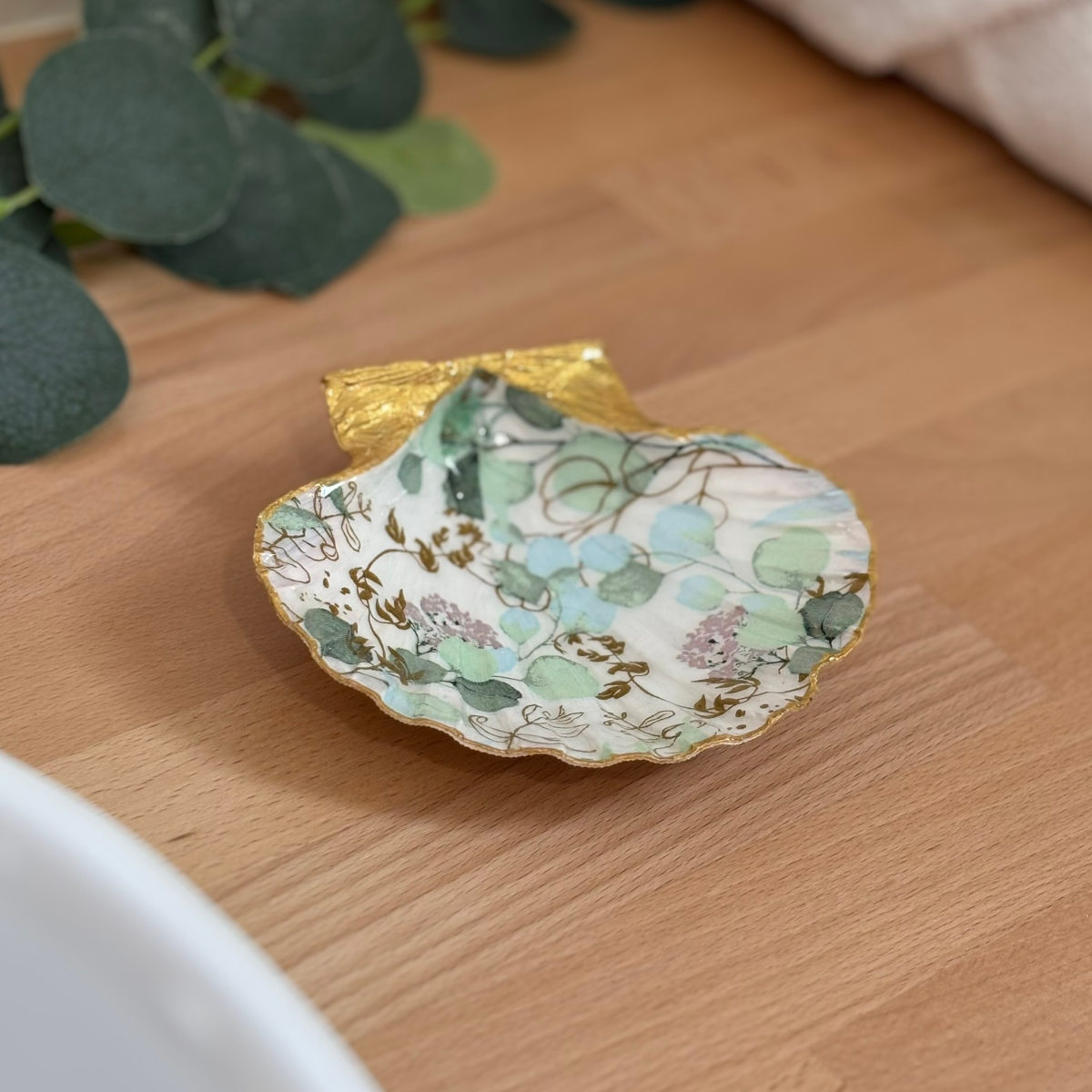 Mise en ambiance Repose bijoux original coquillage feuillage vert sauge en décoration sur meuble bois.