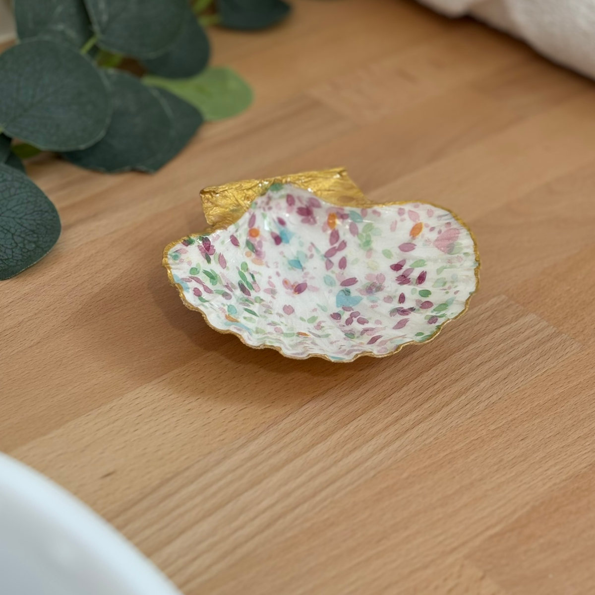 Mise en ambiance Repose bijoux original coquillage pétales pastel en décoration sur meuble bois.
